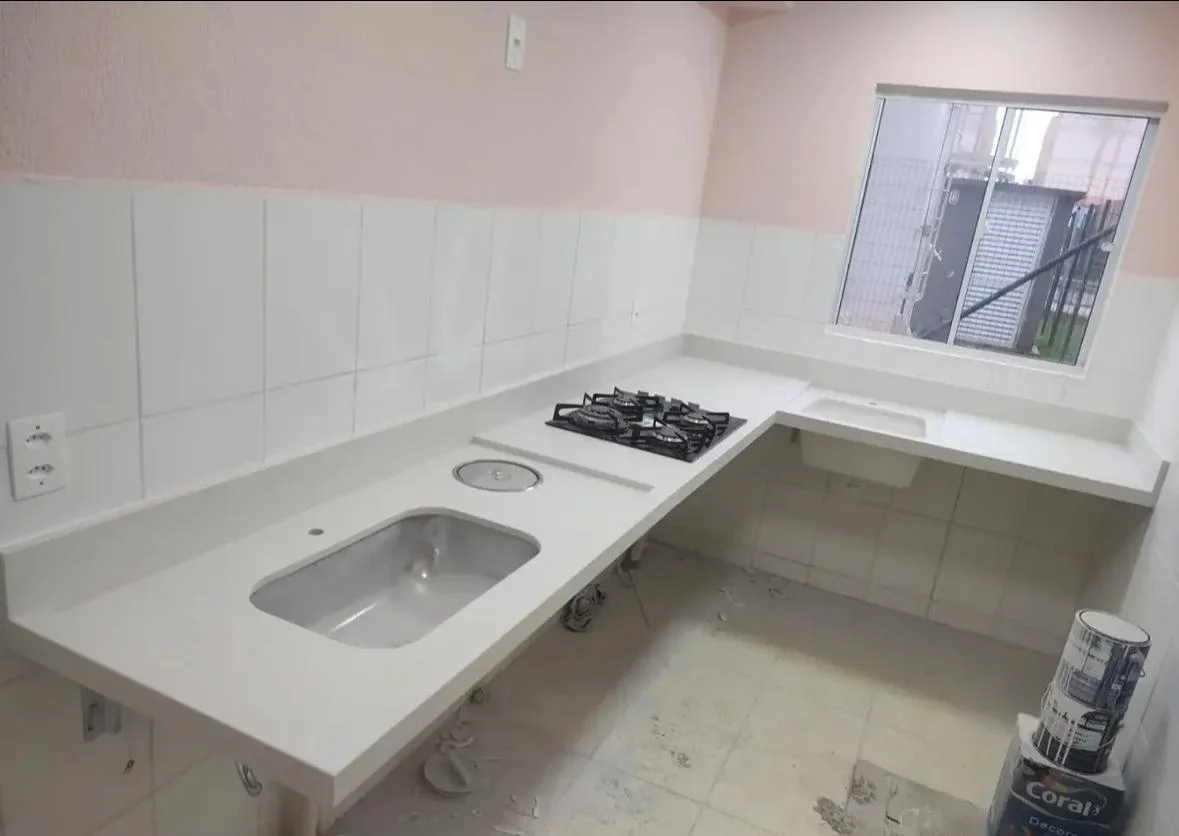 Bancada branca sob medida em L com cuba, cooktop e recortes integrados