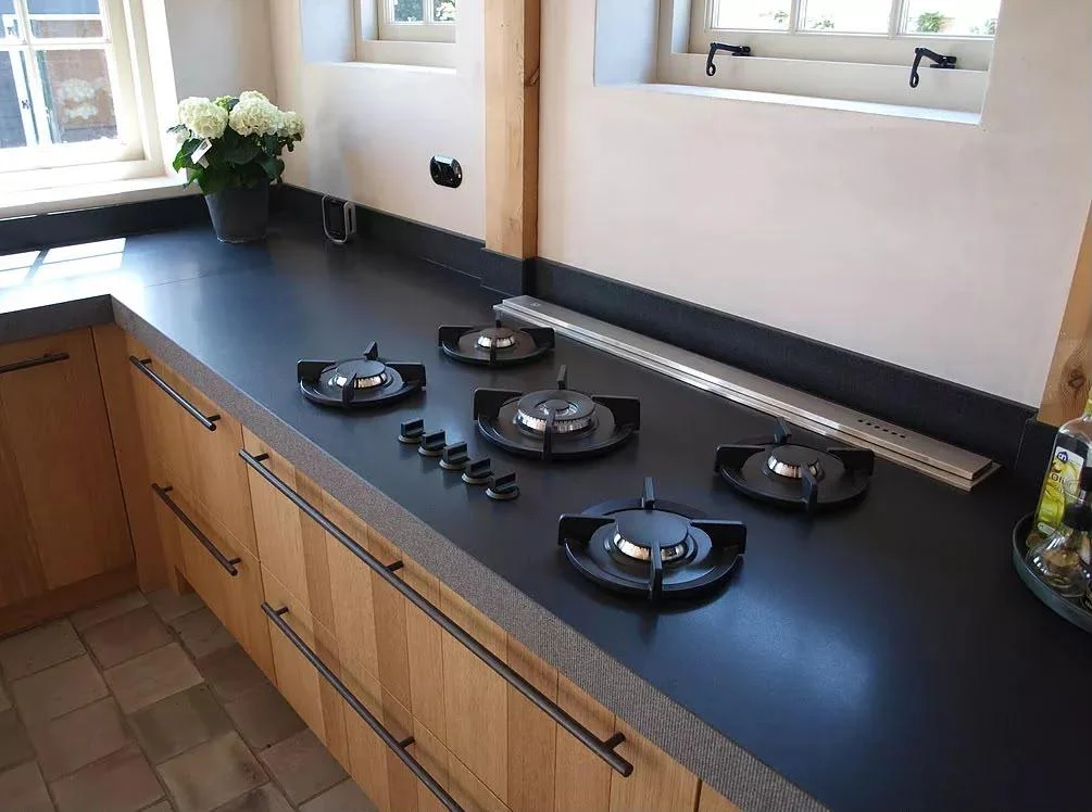 Bancada escura com cooktop e marcenaria em madeira