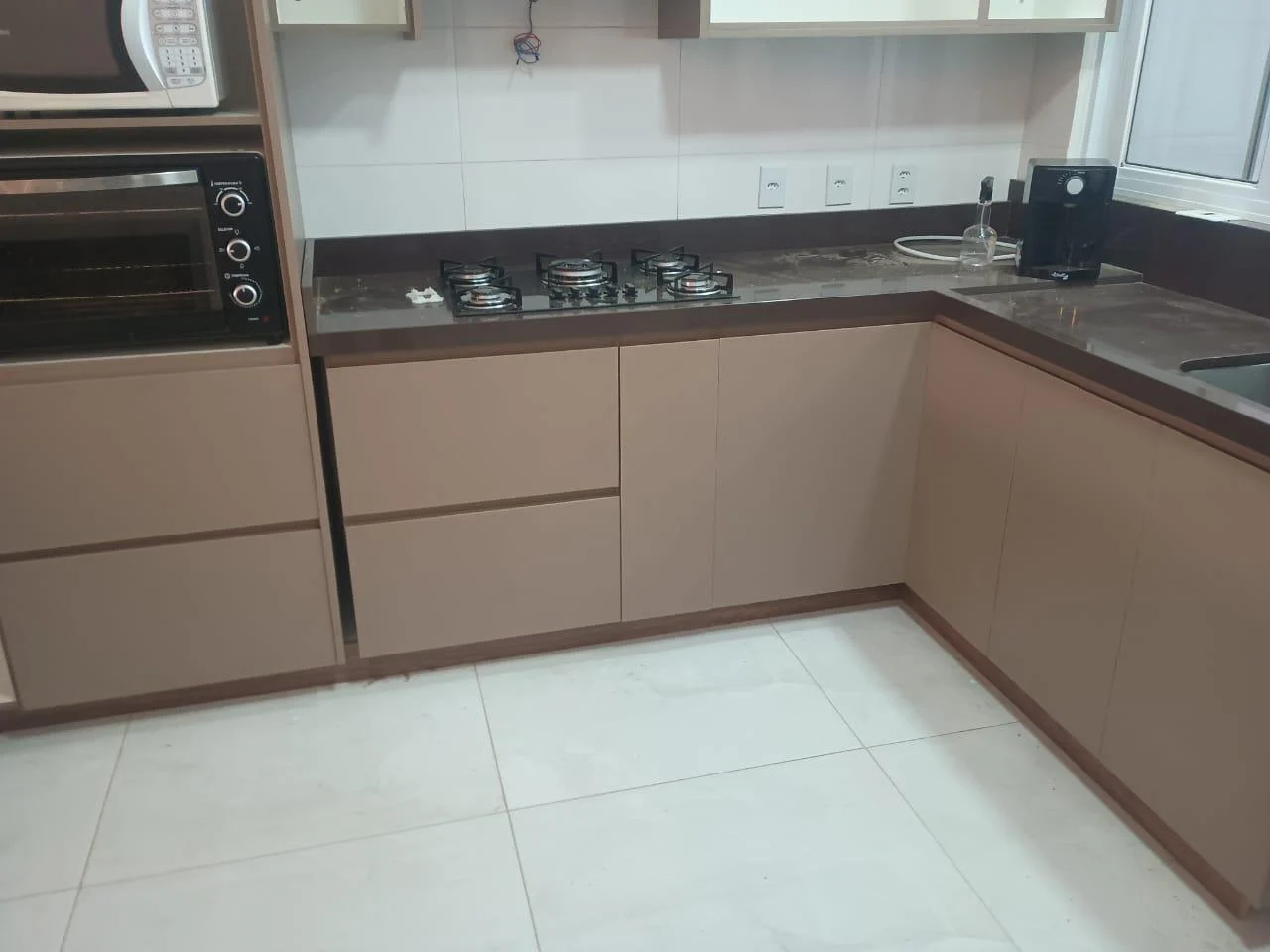 Cozinha com bancada escura em L e armários em tom amadeirado
